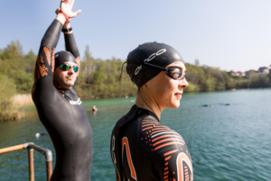 A man and woman in wetsuits ready to open water swim.